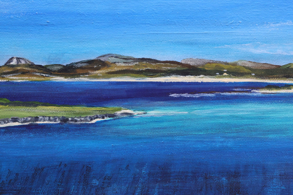 Coastal landscape with blue water and green hills under a clear sky