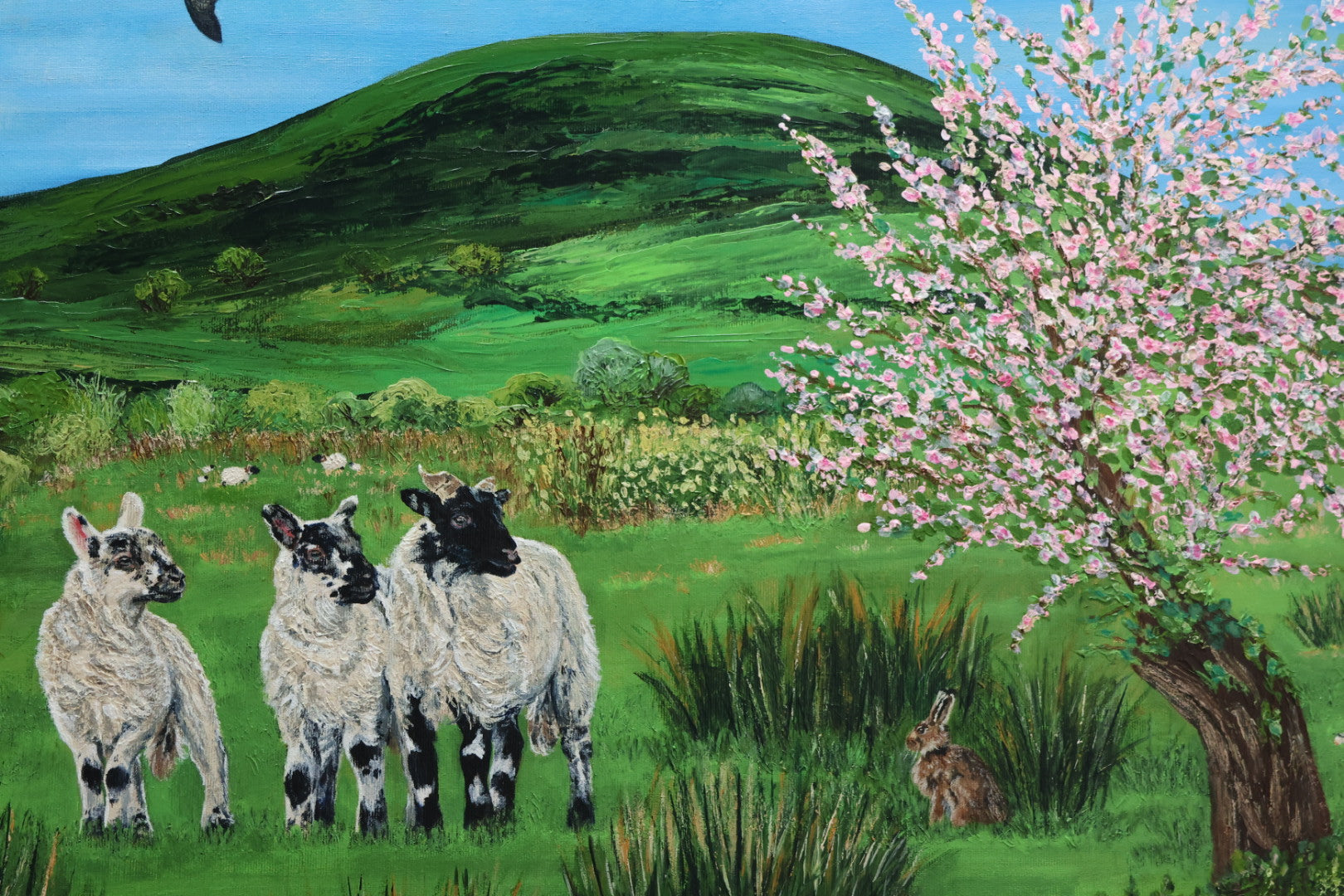 Three lambs and an Irish Hare  in a pastoral scene with a flowering tree and rolling hills.